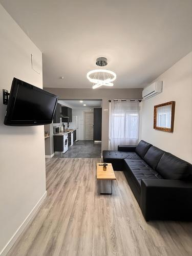 a living room with a black couch and a flat screen tv at Apartamento Sofía II a 500m de la playa in Puerto de Sagunto