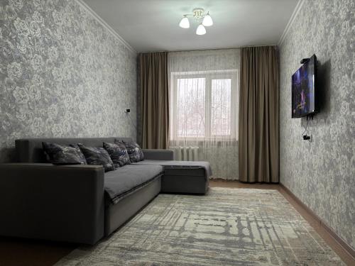 een woonkamer met een bank en een raam bij 2х комнатная квартира в Центре города in Semey