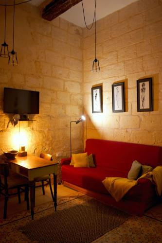 a living room with a red couch and a table at Myrtle Suite - Authentic Valletta Experience in Valletta