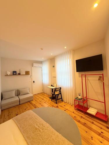 a living room with a bed and a flat screen tv at O Laranjal in Guimarães