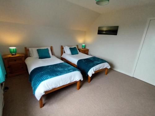 two beds in a room with green lamps on the wall at Tigh a' Chreagain in Stockinish Island