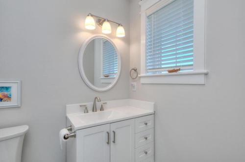 a white bathroom with a sink and a mirror at Aloweha in Oak Island