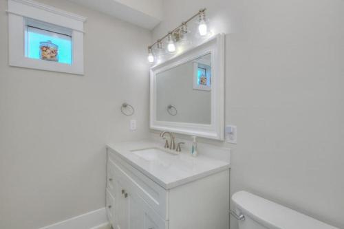 a white bathroom with a sink and a mirror at Aloweha in Oak Island