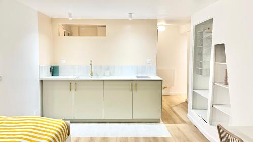une cuisine avec des armoires blanches et un évier dans l'établissement Charming Bright Studio in Ménilmontant, à Paris