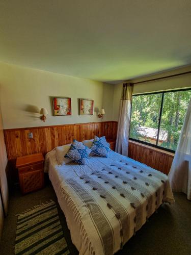 a bedroom with a bed and a large window at Departamento en Pucón - Camino al Volcan in Pucón
