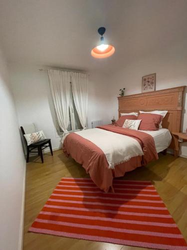 - une chambre avec un grand lit et un tapis rouge dans l'établissement Appartement le Beauséjour, à Arnouville-lès-Gonesse
