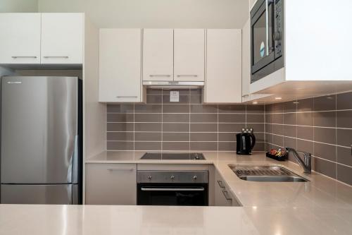 a kitchen with white cabinets and a stainless steel refrigerator at Mercure Kooindah Waters Central Coast in Wyong