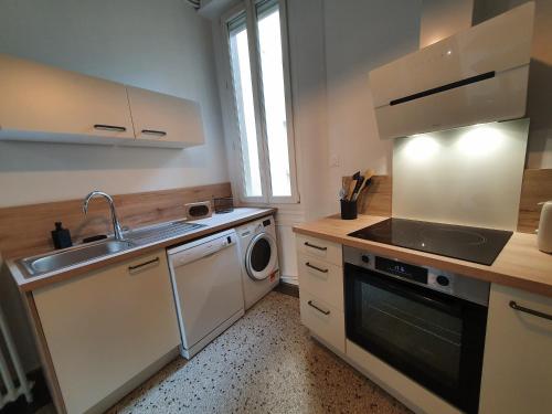 une cuisine avec un évier et une machine à laver dans l'établissement VUE EXCEPTIONNELLE sur la CATHÉDRALE, haut standing et garage privé, à Reims