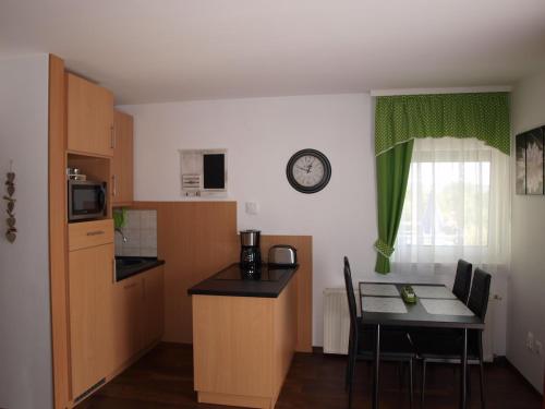 a kitchen with a table and a clock on the wall at Aquarosa Apartman in Hévíz