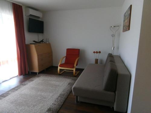 a living room with a couch and a red chair at Aquarosa Apartman in Hévíz