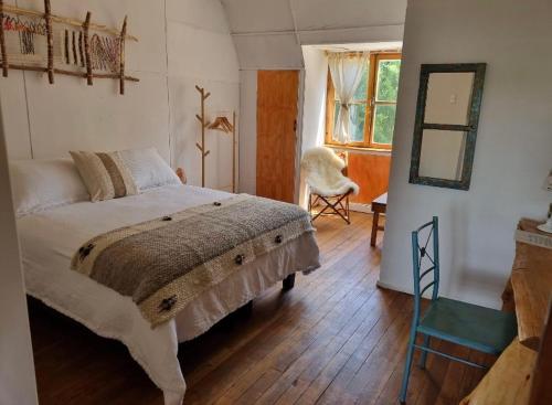 a bedroom with a bed and a chair and a window at Casona Belga Hotel Boutique y Restaurante in Chile Chico