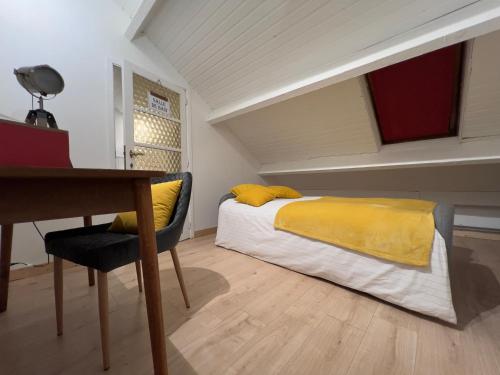 a bedroom with a bed with yellow sheets and a desk at Maison bel-étage à Wavre in Wavre