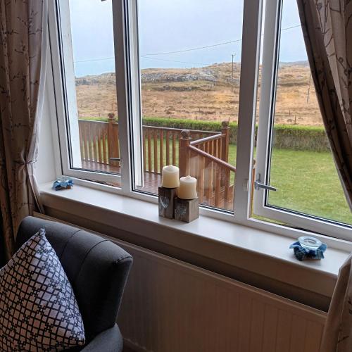 a window with two candles sitting on a window sill at Tigh a' Chreagain in Stockinish Island