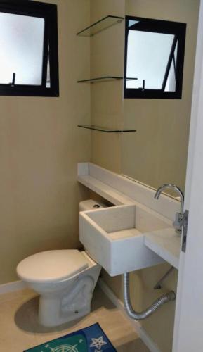 a bathroom with a white toilet and a sink at Triplex Guarujá in Guarujá
