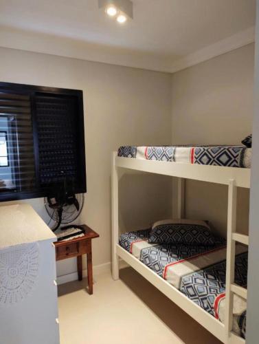 a room with two bunk beds and a television at Triplex Guarujá in Guarujá