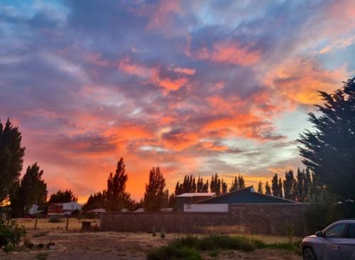 a cloudy sky at sunset with a car in a field at Casona Belga Hotel Boutique y Restaurante in Chile Chico