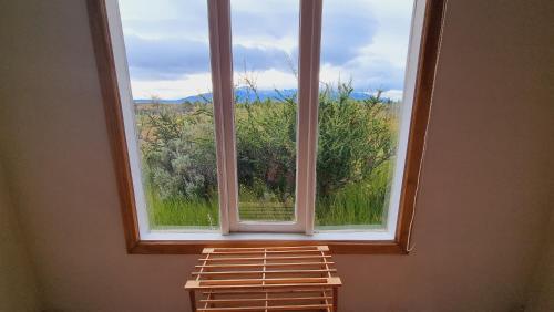 a large window with a view of a field at Cabaña Ecológica El Puesto in Puerto Natales