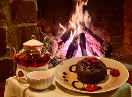a table with a plate of chocolate cake and a fireplace at Casona Belga Hotel Boutique y Restaurante in Chile Chico