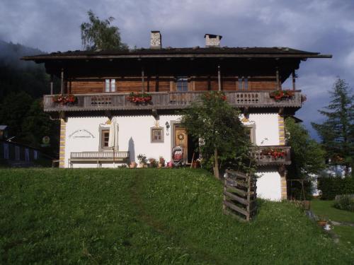 ein Haus auf einem Hügel mit einer Bank davor in der Unterkunft Bauernhof im Wiesengrund in Maria Luggau