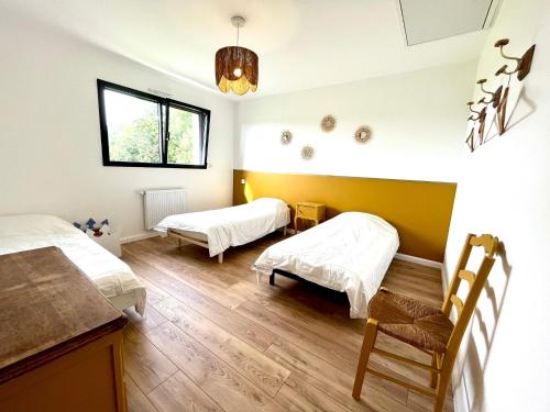 a bedroom with two beds and a chair in it at Villa entre Terre et Mer in Hauteville-sur-Mer
