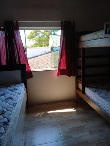 a room with two bunk beds and a window at Casa para temporada Peruíbe - SP in Peruíbe