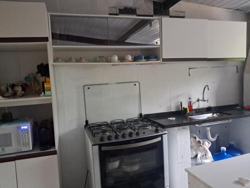 a small kitchen with a stove and a microwave at Casa Confortável Próximo a Lindas Praias in São Sebastião