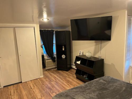 a bedroom with a large flat screen tv on the wall at Charming NYC apt near UBS and Belmont Park Village in Elmont