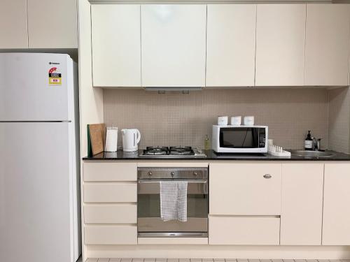 a kitchen with white cabinets and a stove and a microwave at North Sydney apartment with free parking in Sydney