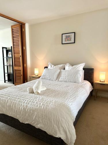 a bedroom with a large white bed with two lamps at North Sydney apartment with free parking in Sydney