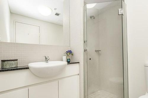 a white bathroom with a sink and a shower at North Sydney apartment with free parking in Sydney