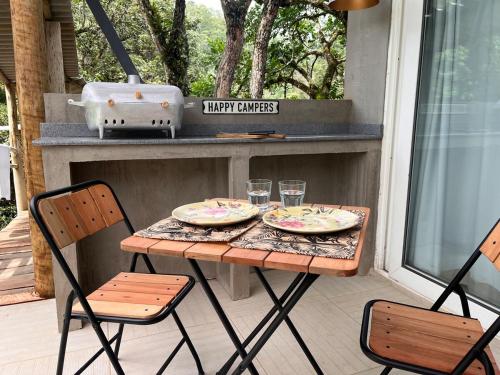 a table with two plates and two chairs on a porch at Refugio Jabuticaba - CASA DA ÁRVORE - Conforto em meio a natureza in Santo Antônio do Pinhal