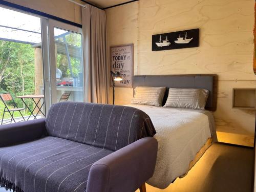 a bedroom with a bed and a couch and a window at Refugio Jabuticaba - CASA DA ÁRVORE - Conforto em meio a natureza in Santo Antônio do Pinhal