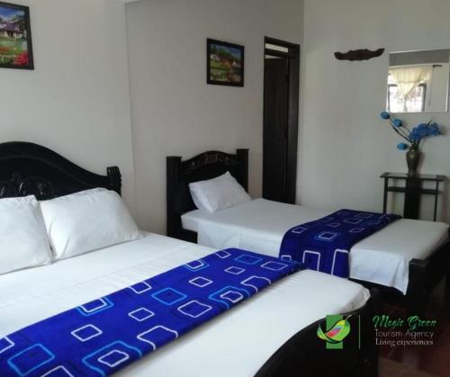a bedroom with two beds with blue and white sheets at HOTEL CAMPESTRE CARRIEL QUINDIO picnic in Montenegro