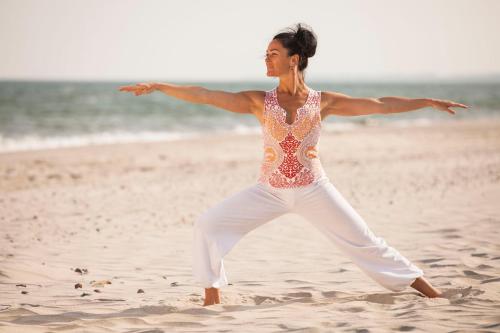 a woman is dancing on the beach at Strandhotel Dünenmeer - Adults only in Dierhagen