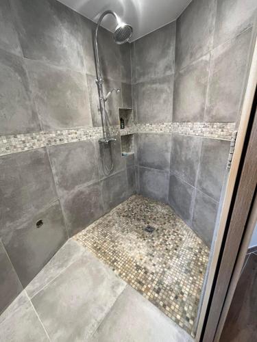 une salle de bain avec une douche avec une porte vitrée dans l'établissement Maison des mûriers, au Luc