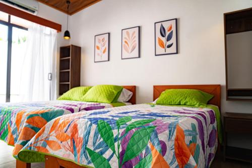 a bedroom with two beds with green pillows at Villas y Casa Dìwö - Puerto Viejo in Hone Creek