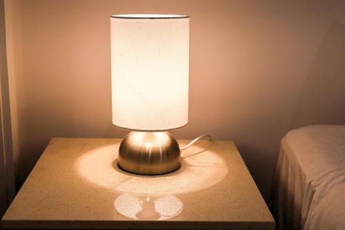 a lamp sitting on a table next to a bed at StayAU Convenient Apartment with Patio in Box Hill in Box Hill