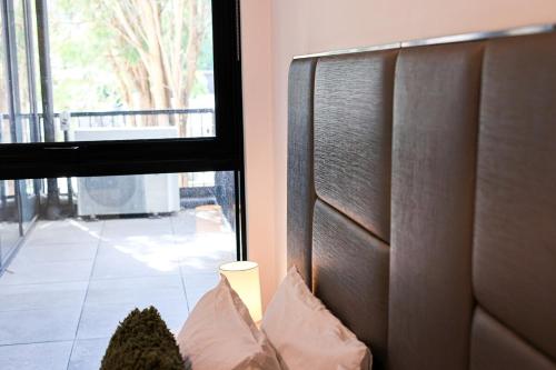 a room with a headboard and a window with a view at StayAU Convenient Apartment with Patio in Box Hill in Box Hill