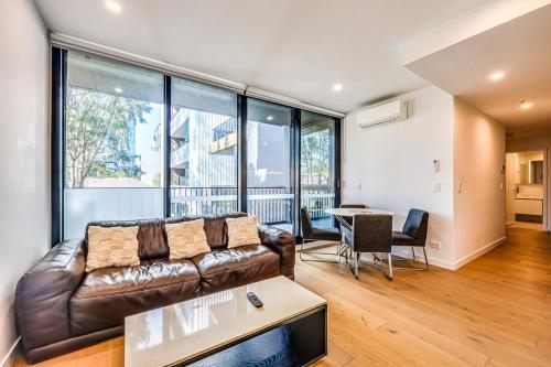 a living room with a leather couch and a table at StayAU Convenient Apartment with Patio in Box Hill in Box Hill