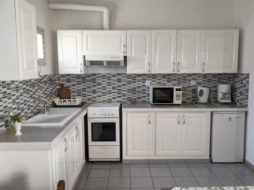a kitchen with white cabinets and white appliances at Herifanja appart et Salama appart in Antsirabe