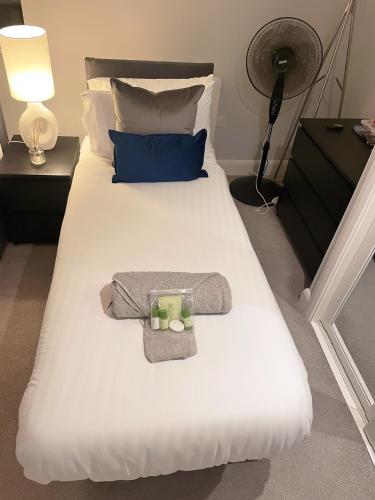 a white bed with a bow tie and towels on it at Super Luxe Central Maidenhead Apartment in Maidenhead