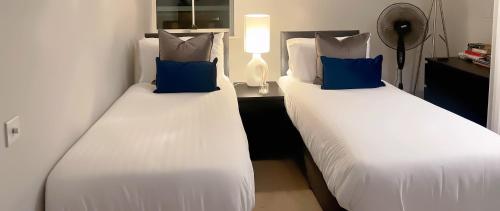 two beds with blue pillows in a hotel room at Super Luxe Central Maidenhead Apartment in Maidenhead