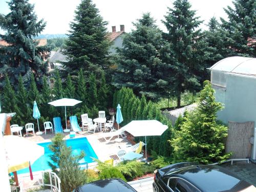 an outdoor swimming pool with umbrellas and chairs at Apart Hévízi Ház in Hévíz