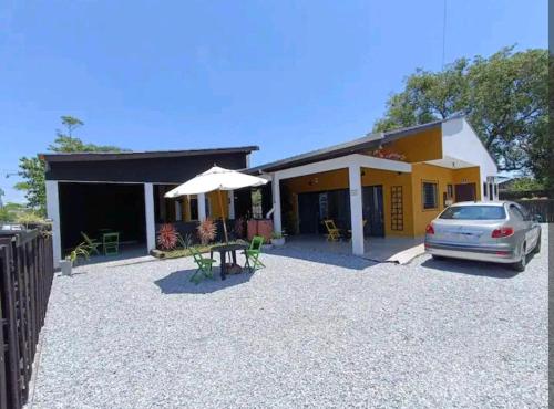 une voiture garée devant une maison avec un parapluie dans l'établissement Quarto 2 Privado Confortável em Pontal do Sul, à Pontal do Paraná