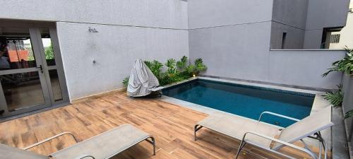 un patio avec une piscine et deux chaises dans l'établissement Studio Aconchegante para 2 pessoas, à São Paulo
