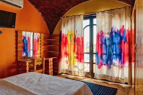 a bedroom with a bed and a window with colorful curtains at Moon of Nuba House in Aswan