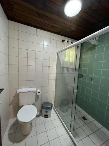 a bathroom with a toilet and a glass shower at Recanto dos Sonhos Guest House in Lumiar