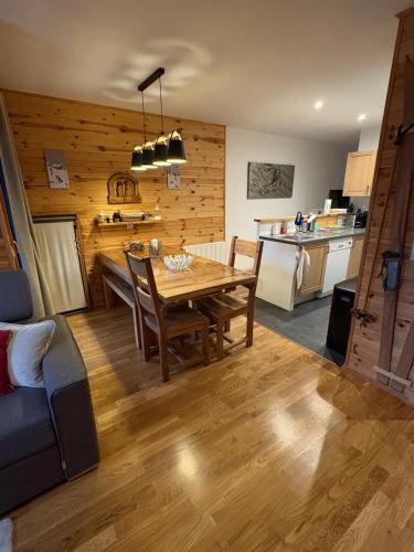 une cuisine et une salle à manger avec une table et des chaises en bois dans l'établissement Location appartement cosy, à La Plagne Tarentaise