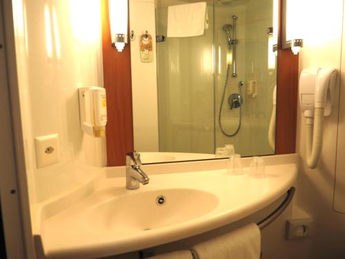 uma casa de banho com um lavatório e um chuveiro com um espelho. em ibis Genève Petit Lancy em Genebra