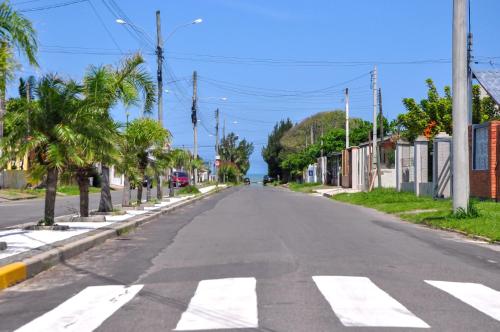 an empty street in a town with palm trees at Casa Com Quatro Dormitórios, Pertinho Do Mar Em Capão Da Canoa in Capão da Canoa
